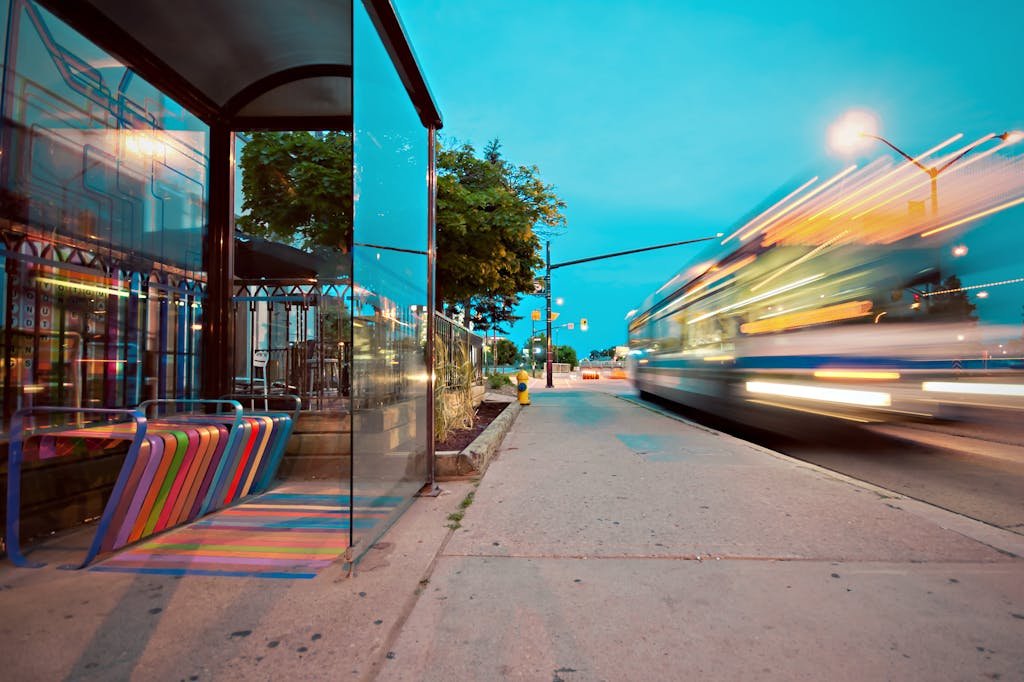 Como o marketing pode impulsionar projetos de infraestrutura urbana 3 Colorful city bus stop with vibrant benches, blurred motion of a passing bus at dusk.