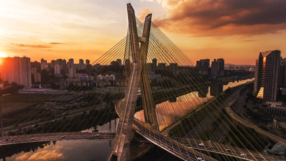 Marketing para Mobilidade Urbana: como sua empresa pode ser relevante em 2025 3 Vista aérea da Ponte Estaiada em São Paulo ao entardecer, com o céu alaranjado e o rio Pinheiros refletindo a luz do pôr do sol.