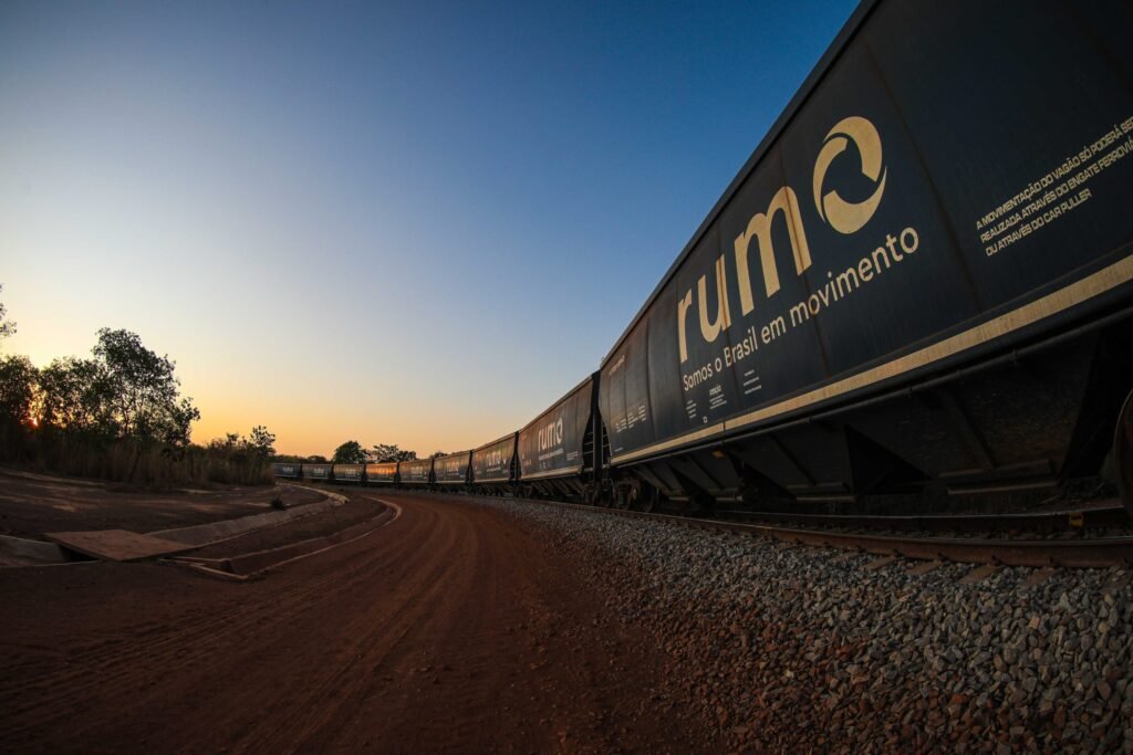 Como conseguir clientes para logística usando marketing digital 4 Trem de carga da Rumo Logística circulando ao entardecer, com a frase “Somos o Brasil em movimento” estampada no vagão.