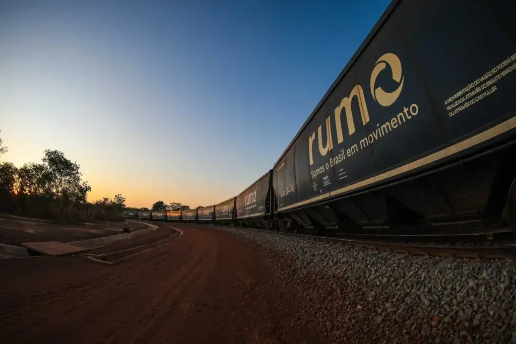 Como conseguir clientes para logística usando marketing digital 4 Trem de carga da Rumo Logística circulando ao entardecer, com a frase “Somos o Brasil em movimento” estampada no vagão.