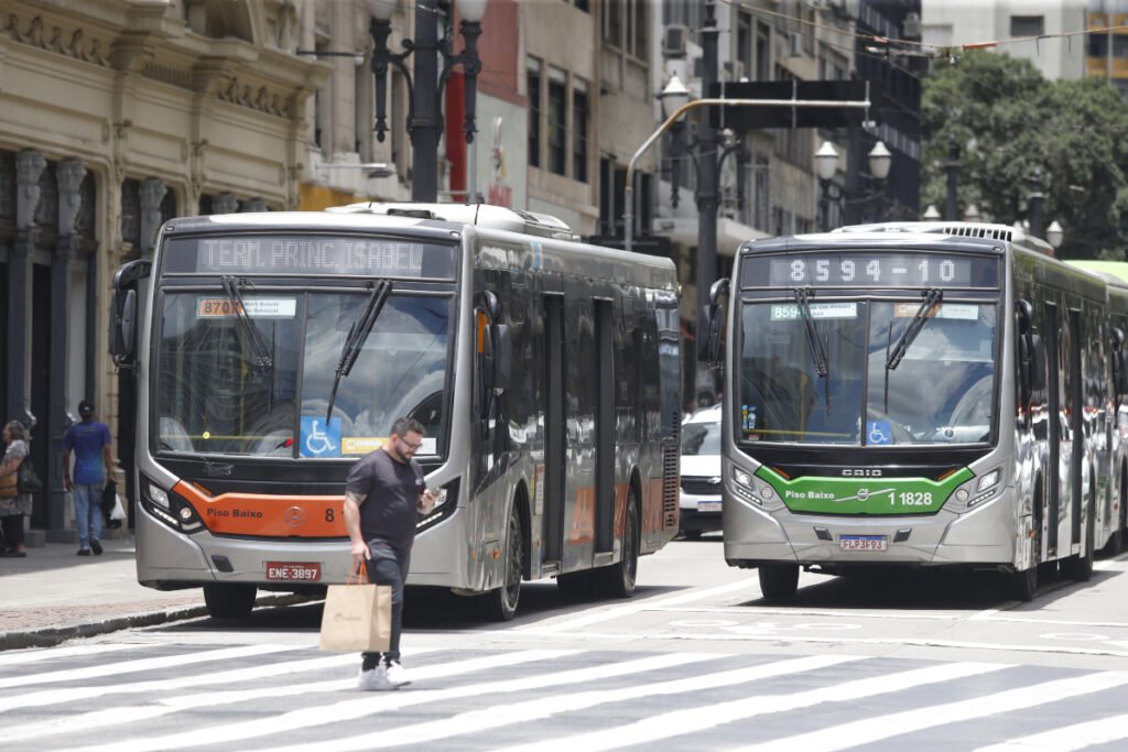 Marketing para Mobilidade Urbana: como sua empresa pode ser relevante em 2025 5 Dois ônibus articulados circulam por avenida no centro de São Paulo, com destaque para a sinalização de acessibilidade e pedestre atravessando na faixa. Marketing para Mobilidade Urbana.