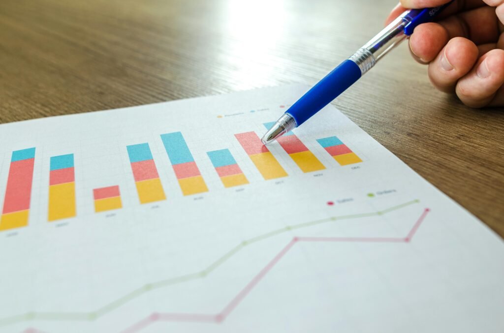Como otimizar a captação de fretes para transportadoras 5 Pessoa analisando gráfico de barras colorido em relatório impresso, representando métricas e KPIs de desempenho.
