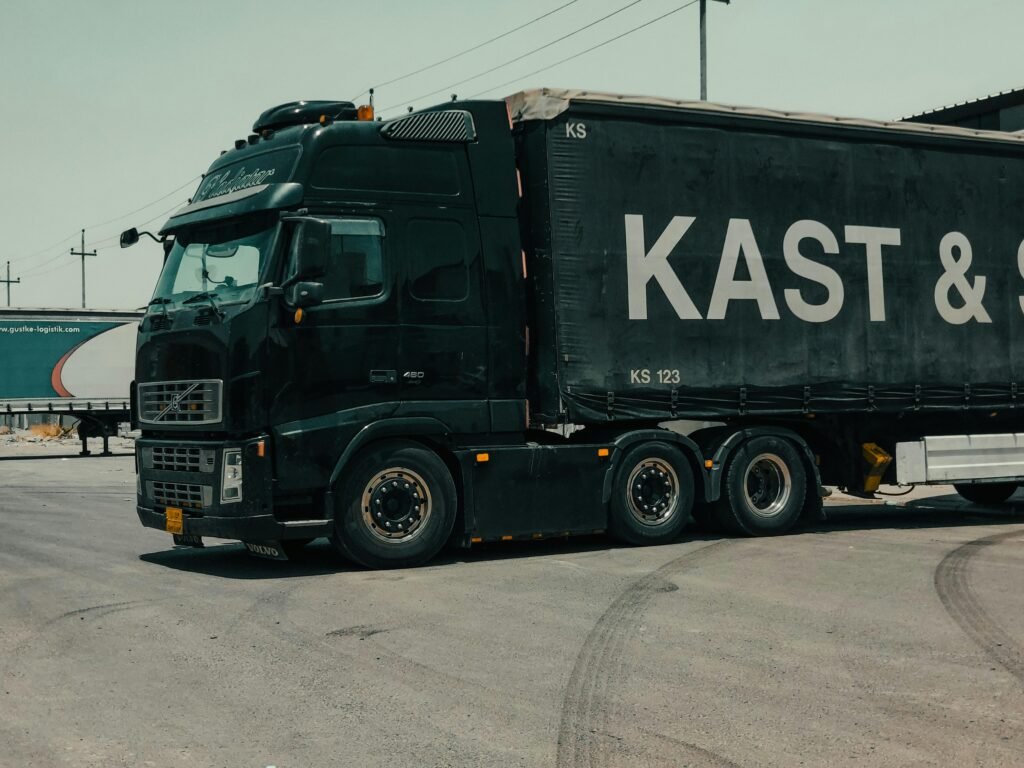 Caminhão baú Volvo realizando transporte rodoviário de cargas em pátio logístico