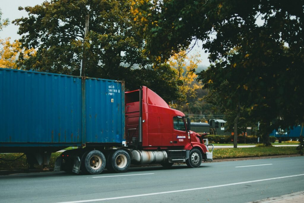 Caminhão vermelho com contêiner azul em via urbana para serviço de transporte de carga